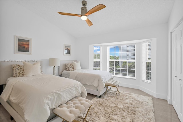 bedroom featuring ceiling fan, lofted ceiling, a textured ceiling, and a closet