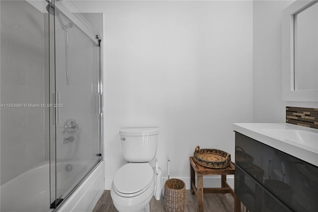 full bathroom featuring toilet, combined bath / shower with glass door, vanity, hardwood / wood-style flooring, and decorative backsplash