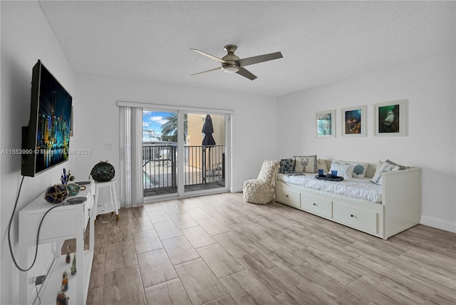 living area featuring ceiling fan, light hardwood / wood-style flooring, and a textured ceiling