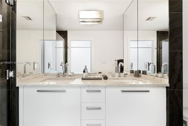 bathroom featuring dual vanity and an enclosed shower