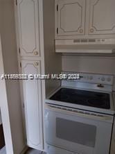 kitchen with exhaust hood, white cabinetry, and stove