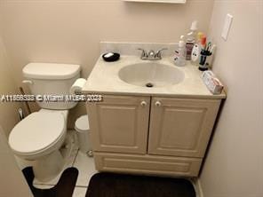 bathroom with toilet, vanity, and tile flooring