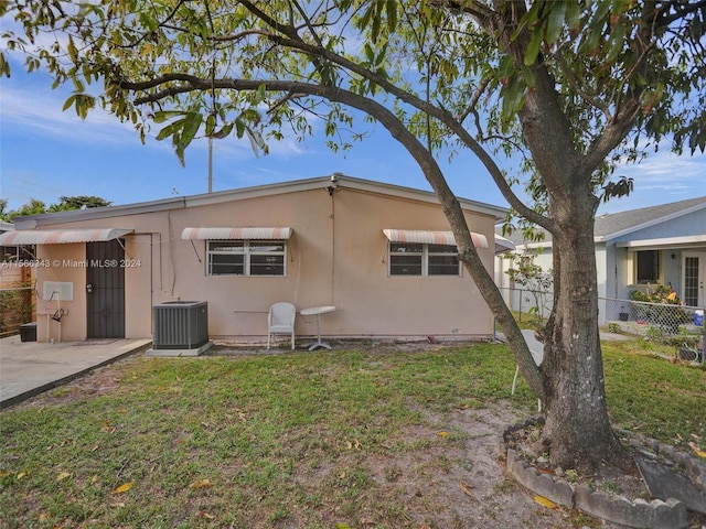 back of house with central AC and a yard