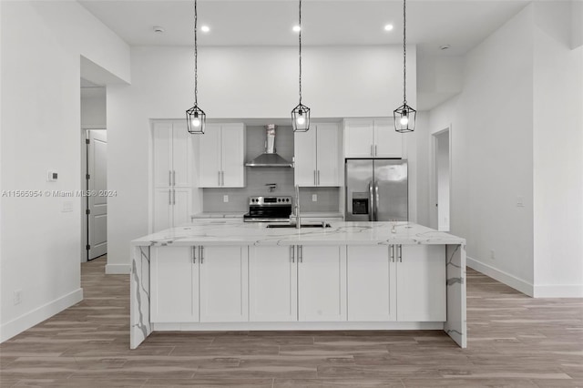 kitchen with a kitchen island with sink, wall chimney exhaust hood, light hardwood / wood-style flooring, and stainless steel appliances