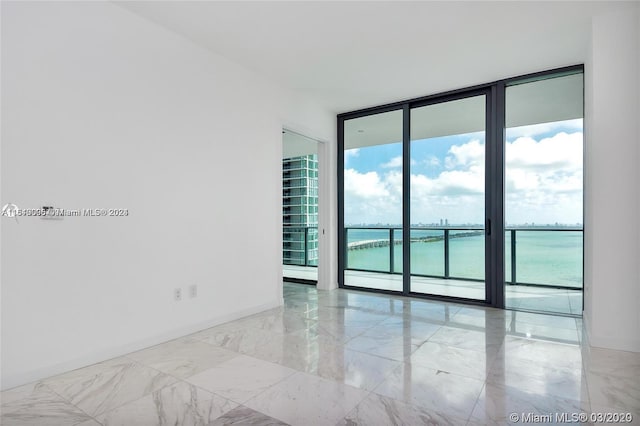 tiled empty room featuring expansive windows and a water view