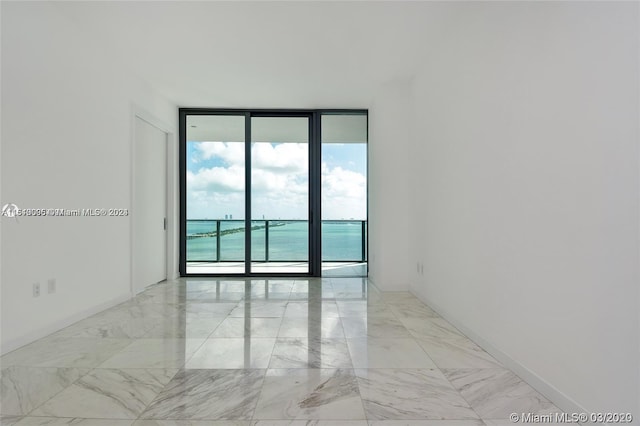 tiled empty room with plenty of natural light, expansive windows, and a water view