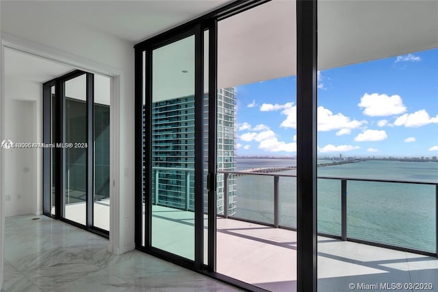 interior space with a water view, light tile floors, and a wall of windows