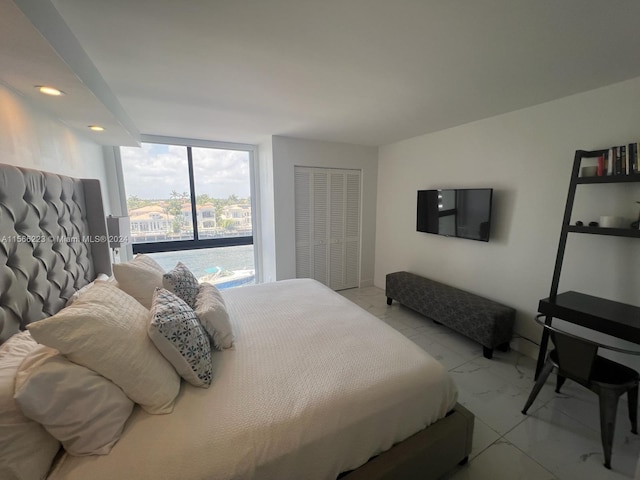 bedroom with a closet, a wall of windows, and tile flooring