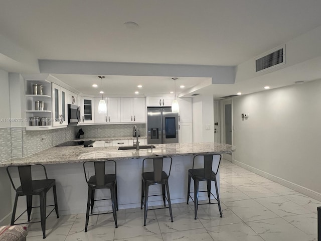 kitchen featuring light tile floors, backsplash, white cabinetry, hanging light fixtures, and stainless steel appliances