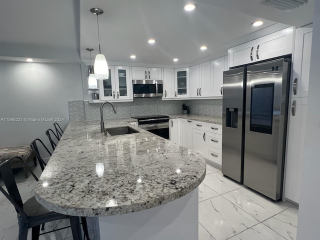 kitchen with kitchen peninsula, hanging light fixtures, stainless steel appliances, tasteful backsplash, and white cabinets