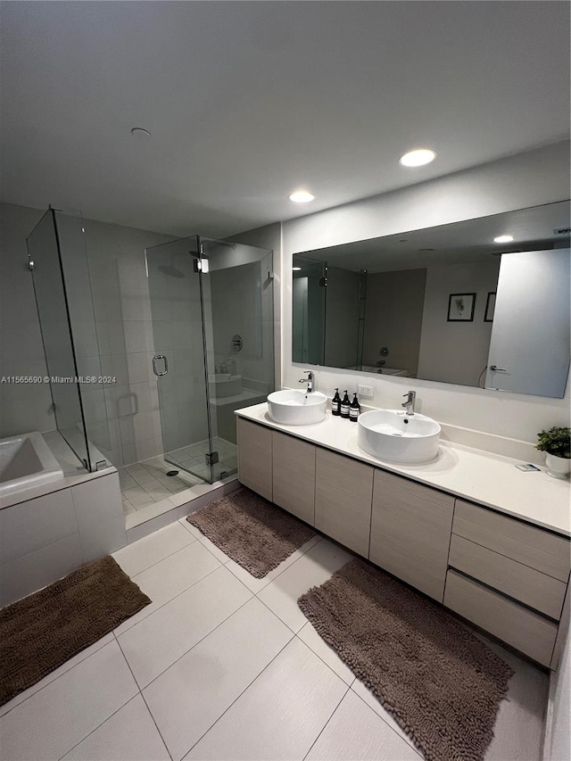 bathroom with a shower with door, dual sinks, large vanity, and tile flooring