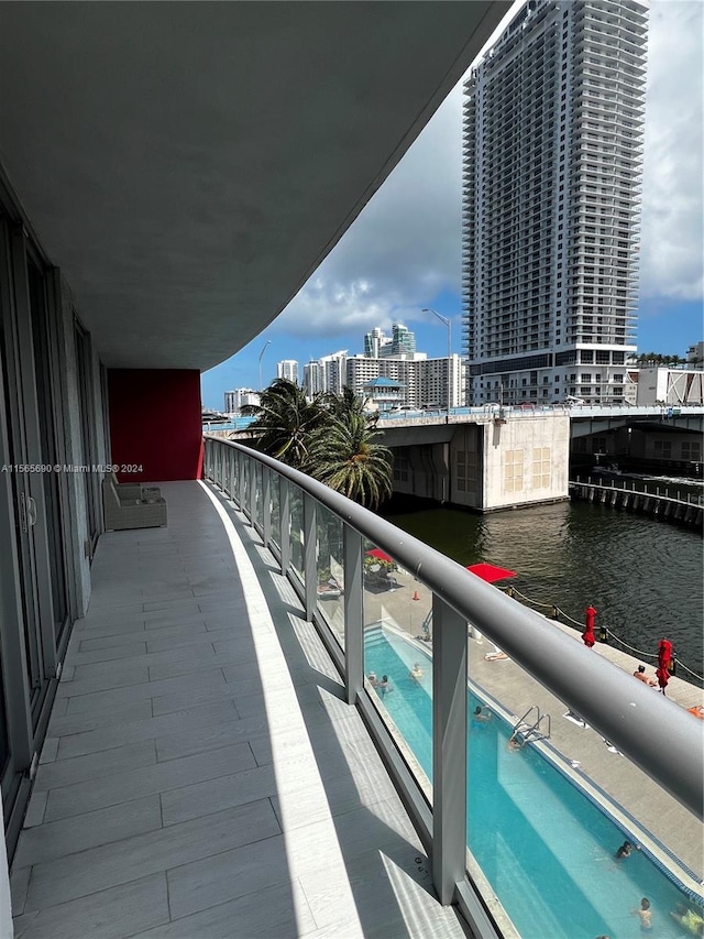 balcony featuring a water view and a community pool