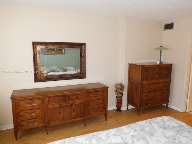 bedroom with a textured ceiling and light wood-type flooring