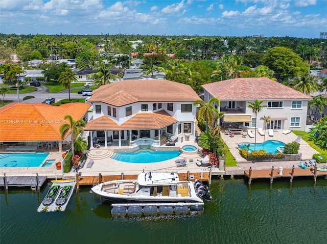 back of property with a swimming pool with hot tub, a water view, a balcony, and a patio