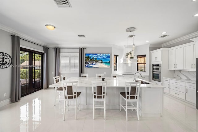 kitchen featuring a spacious island, white cabinets, sink, and pendant lighting