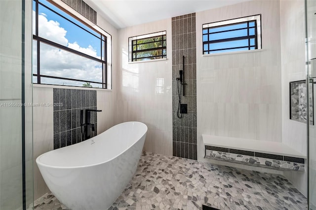 bathroom with plenty of natural light, plus walk in shower, and tile walls