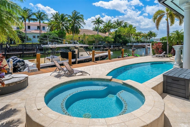 view of pool with an in ground hot tub, a water view, and a boat dock