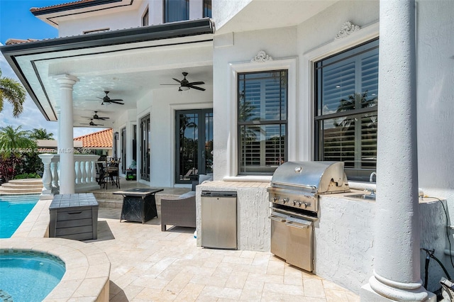 view of patio featuring exterior kitchen, area for grilling, ceiling fan, and an outdoor fire pit