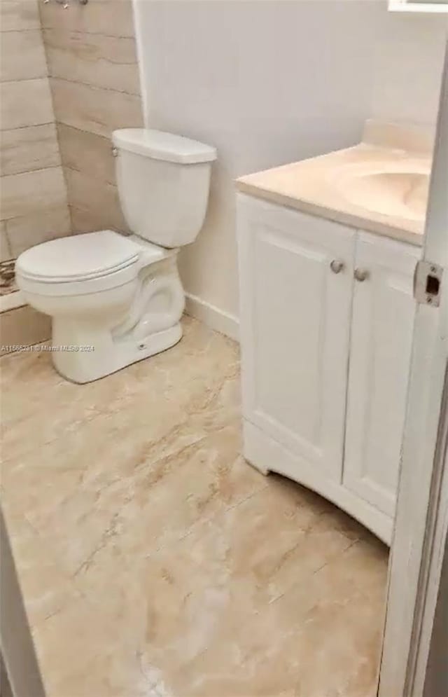 bathroom featuring toilet, tile flooring, and vanity