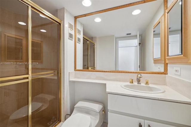 bathroom with vanity, a shower with door, and toilet