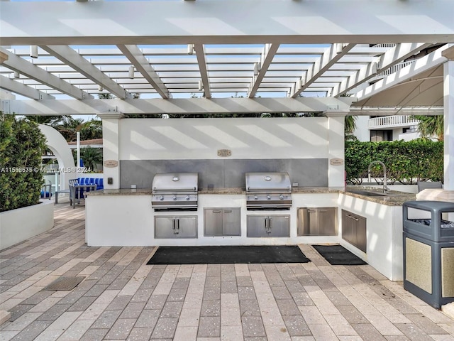 view of patio / terrace with exterior kitchen, area for grilling, sink, and a pergola