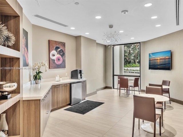 kitchen with hanging light fixtures, a notable chandelier, fridge, and kitchen peninsula