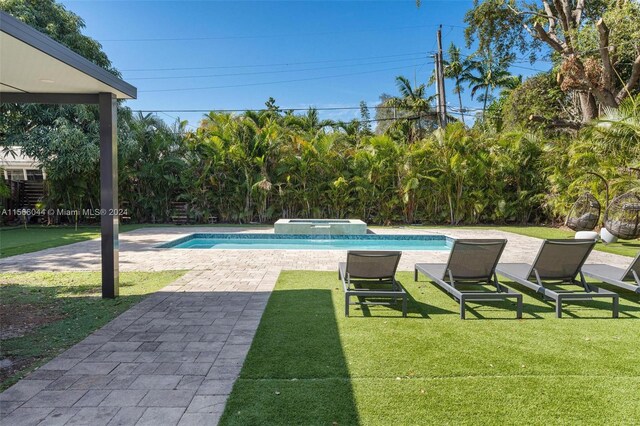 view of pool with a patio, a yard, and an in ground hot tub