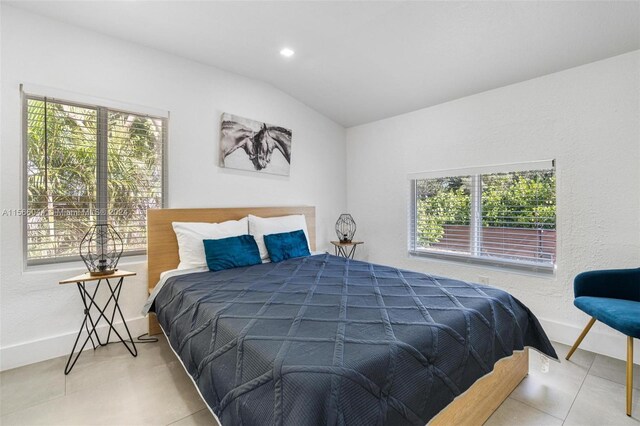 bedroom with multiple windows, lofted ceiling, and light tile patterned flooring