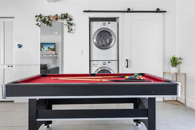 recreation room with light tile patterned floors, a barn door, billiards, and stacked washer and clothes dryer