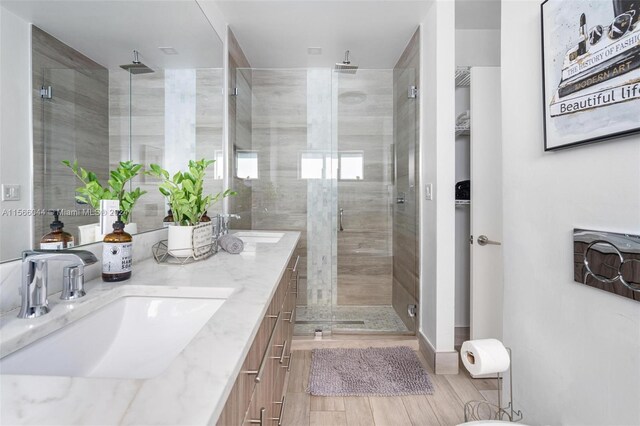 bathroom featuring wood-type flooring, a shower with door, and vanity