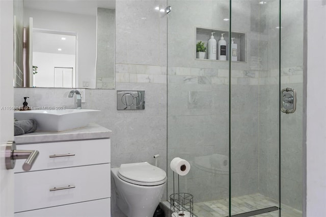 bathroom with tile walls, an enclosed shower, vanity, and toilet