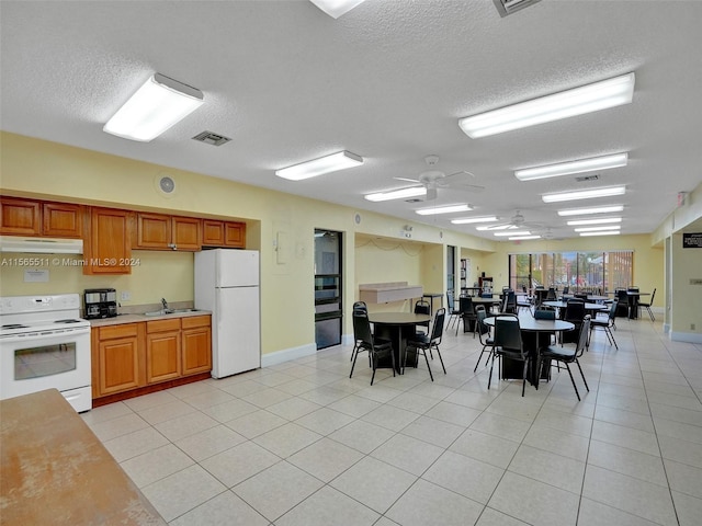 kitchen with light tile floors, a textured ceiling, ceiling fan, white appliances, and sink