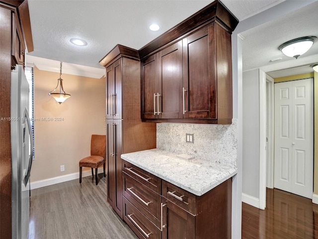 kitchen with pendant lighting, tasteful backsplash, dark wood-type flooring, and light stone counters