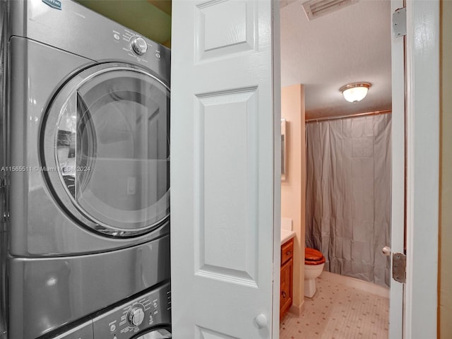 clothes washing area featuring stacked washer and clothes dryer and light tile floors