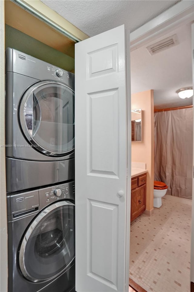 laundry area featuring tile floors and stacked washer and dryer