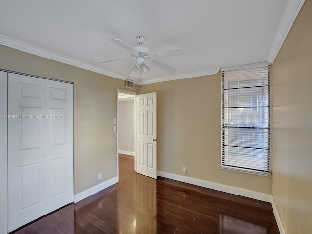 unfurnished bedroom with a closet, crown molding, ceiling fan, and dark hardwood / wood-style flooring