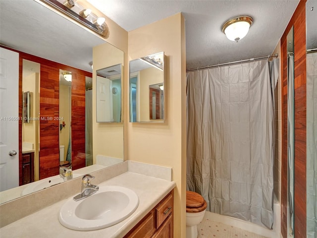 bathroom with tile flooring, toilet, large vanity, and a textured ceiling