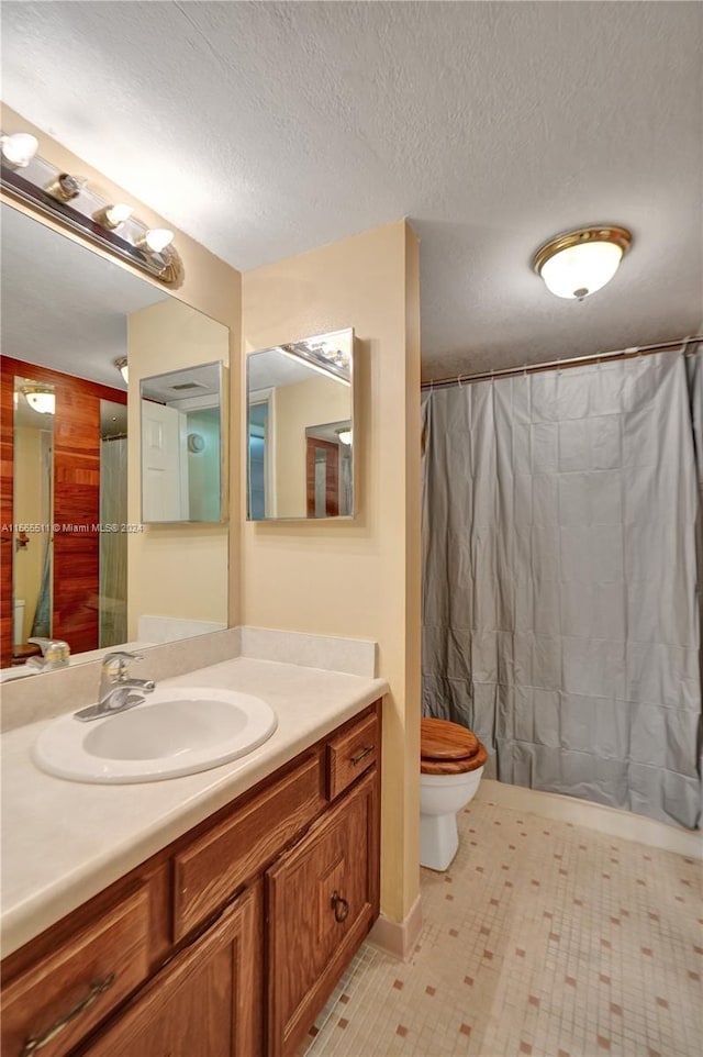 bathroom featuring a textured ceiling, tile floors, large vanity, and toilet