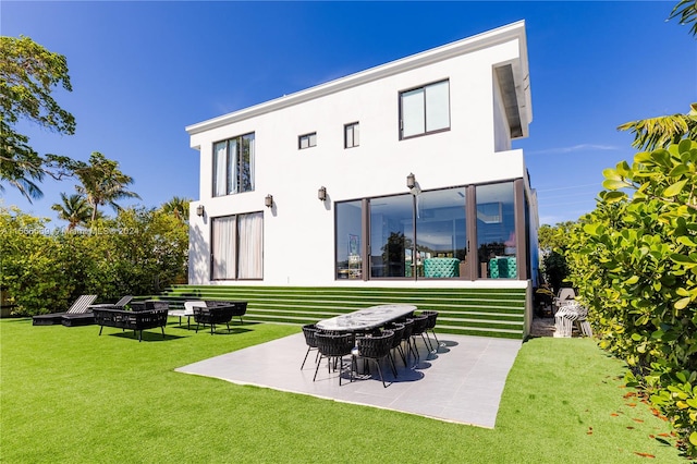 rear view of house with an outdoor fire pit, a patio, and a lawn