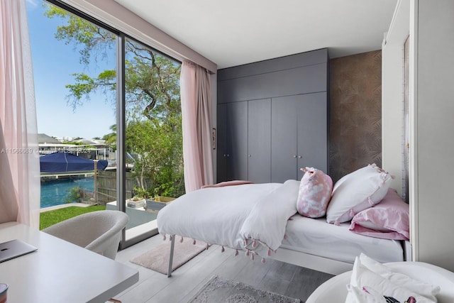 bedroom with a water view and hardwood / wood-style floors