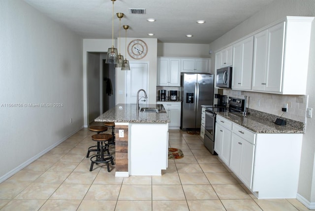 kitchen featuring pendant lighting, stainless steel appliances, dark stone countertops, light tile floors, and white cabinetry