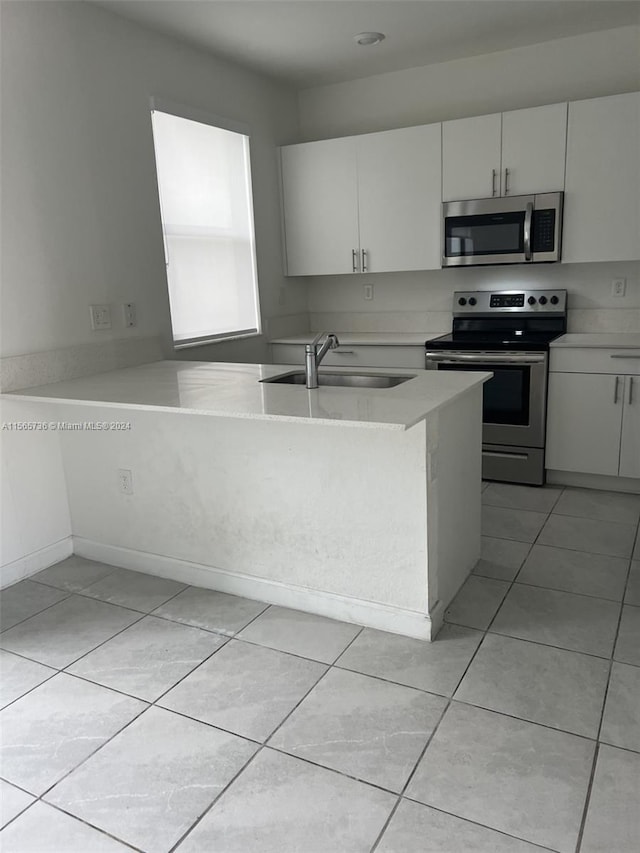 kitchen with appliances with stainless steel finishes, kitchen peninsula, and white cabinetry