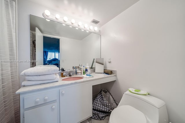 bathroom with toilet and vanity with extensive cabinet space