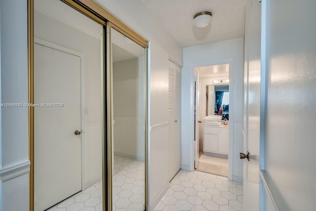 hall with light tile flooring and a textured ceiling