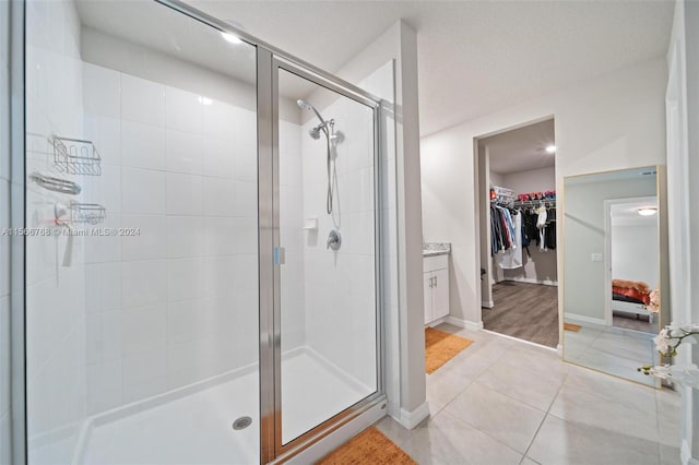 bathroom with walk in shower, vanity, and tile patterned floors