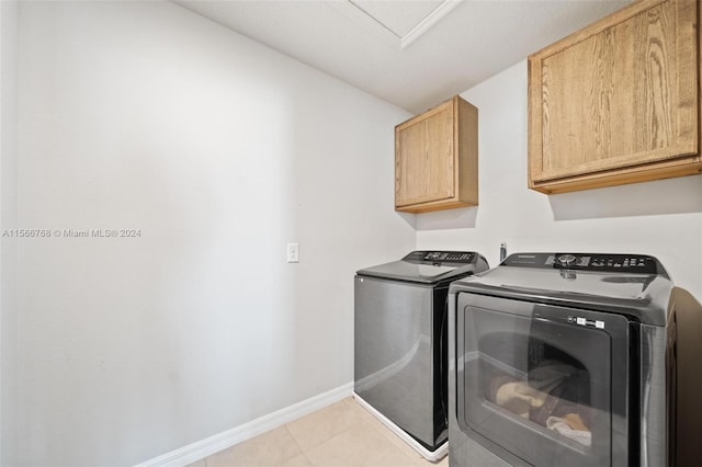 washroom featuring cabinets, light tile patterned floors, and washing machine and clothes dryer