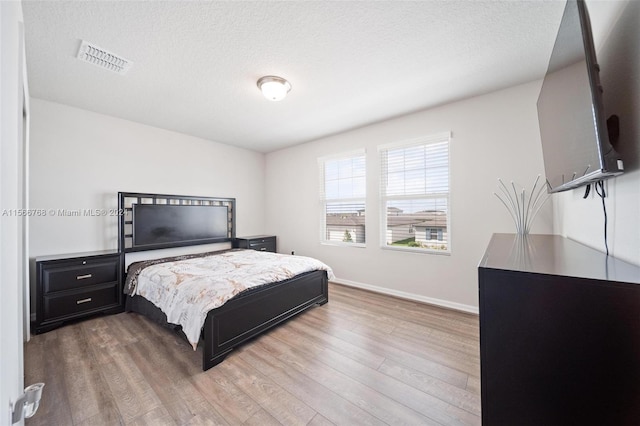 bedroom with a textured ceiling and hardwood / wood-style flooring