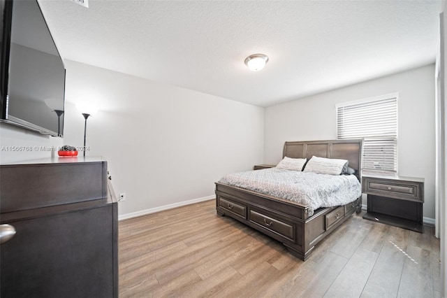 bedroom featuring a textured ceiling and light hardwood / wood-style floors