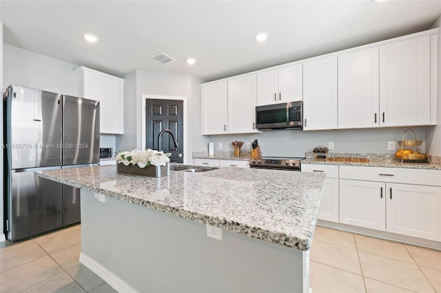 kitchen with appliances with stainless steel finishes, a kitchen island with sink, and white cabinetry