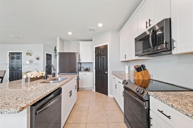 kitchen featuring white cabinets, light tile patterned flooring, sink, a kitchen island with sink, and appliances with stainless steel finishes